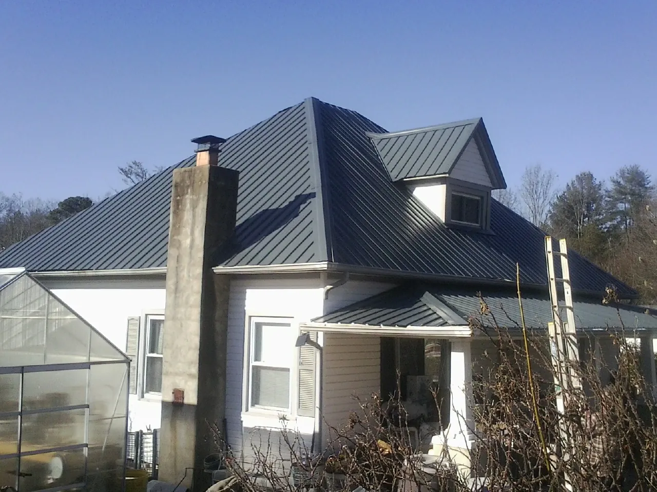 Dark blue standing seam metal roof on a white farmhouse with dormer — Slate & Tile Roof Repair by Roofing Brothers in Losantville