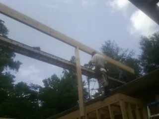 Carpenter setting a ridge beam over a new addition frame — Ice Dam Removal by Roofing Brothers in Losantville