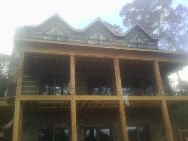 Dormers and porch framing on a large log home under construction — Roof Coating work by our crew in Losantville