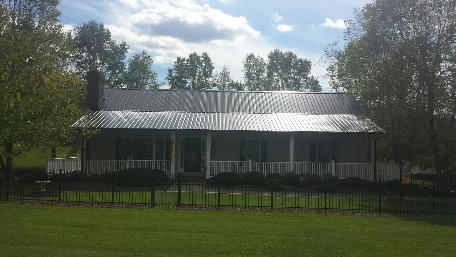Gray metal roof on a brick ranch with a full width front porch — Gutter Guard Installation work by our crew in Losantville