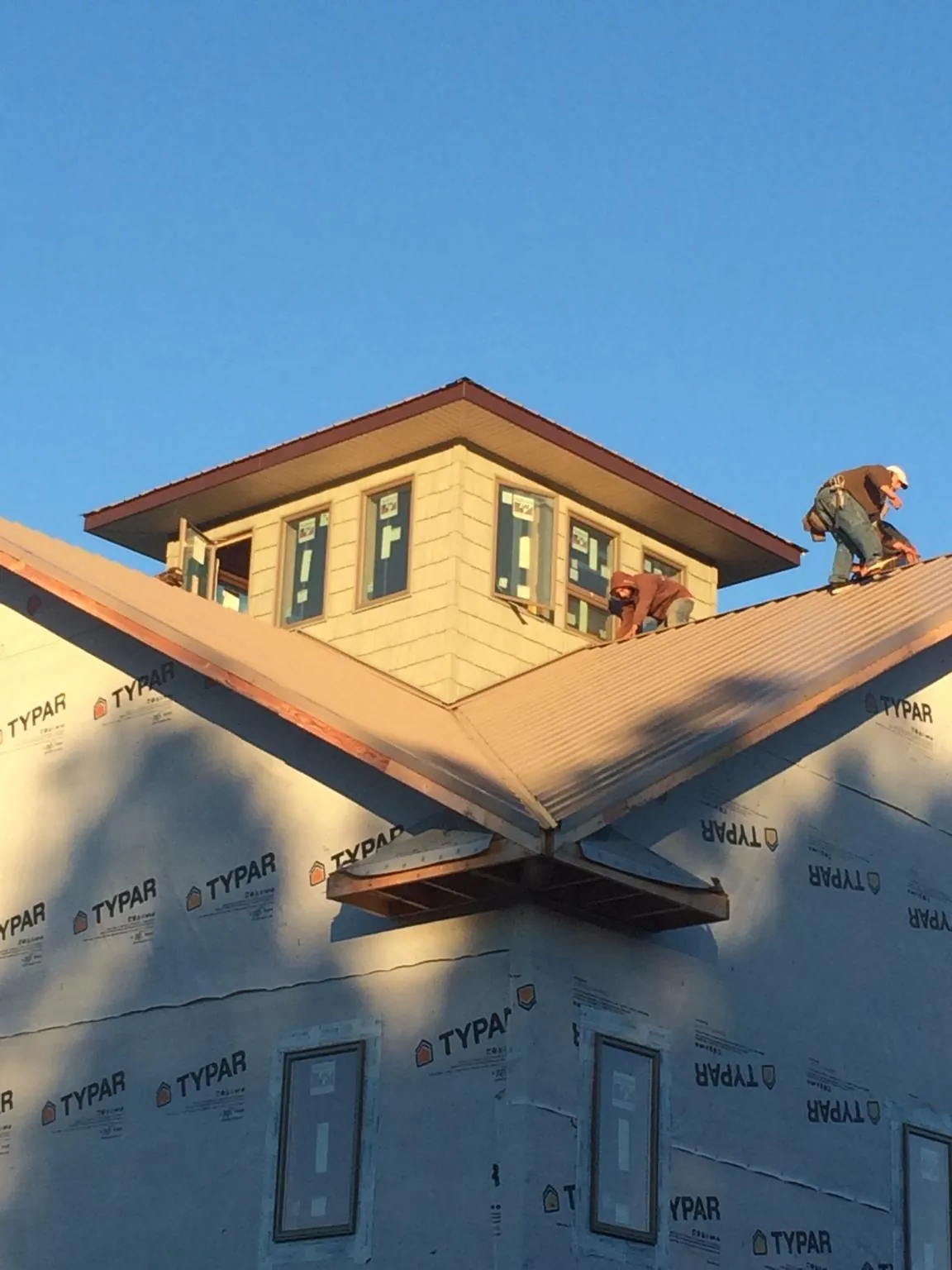 Roofers working around a rooftop cupola on a new metal roof at sunset — Roof Waterproofing in Losantville by Roofing Brothers